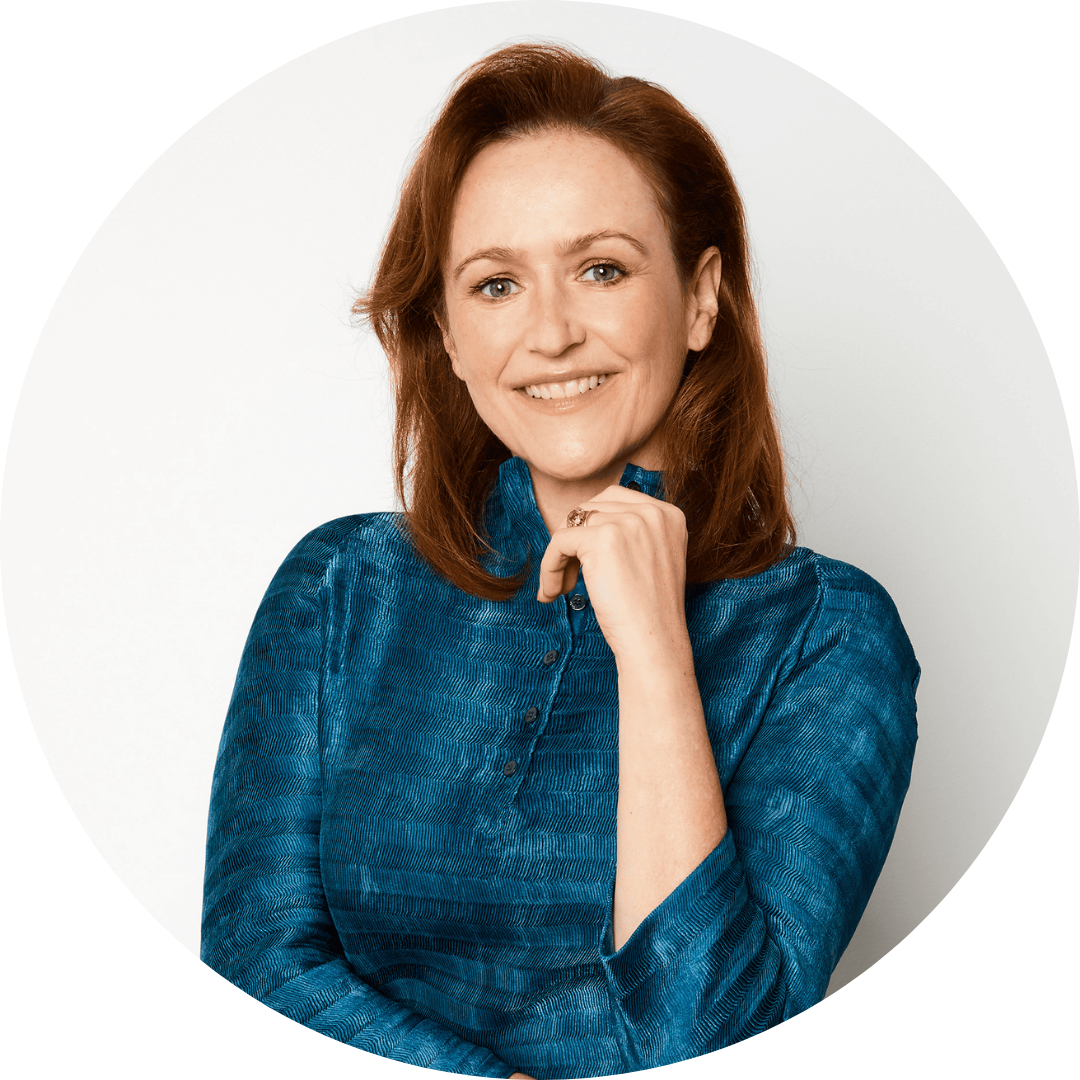 Meredith Kelly headshot Head-and-shoulders portrait of Meredith Kelly, wearing a teal-blue blouse and resting one hand near her chin, shown against a light background within a circular frame.