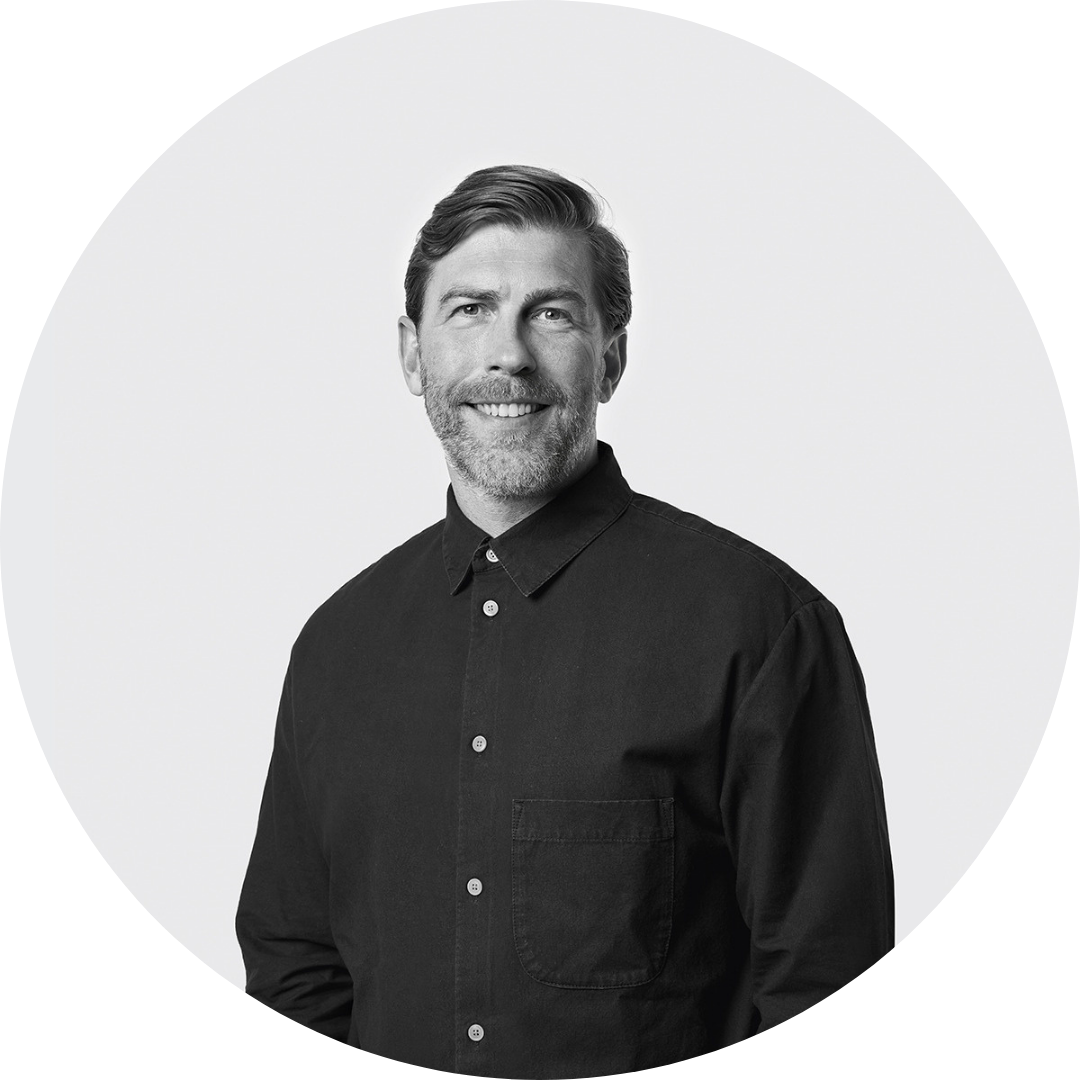 Sven Huberts headshot Black-and-white head-and-shoulders portrait of Sven Huberts, smiling at the camera and wearing a black button-up shirt, shown against a light background within a circular frame.